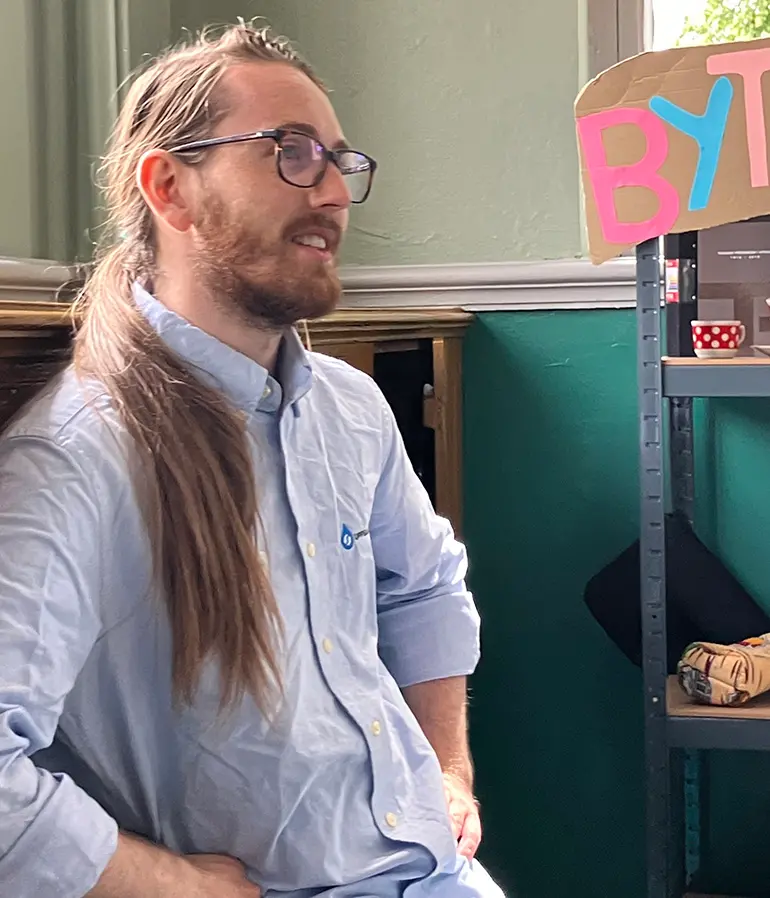 Elias framför byteshyllan för återbruk på Pumphuset.