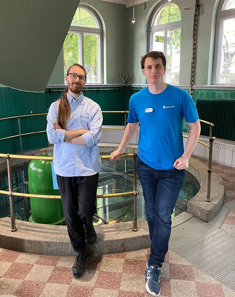Per och Eliar sommarjobbar i Pumphuset, de står framför samlingsbrunnen i entrén till muséet.